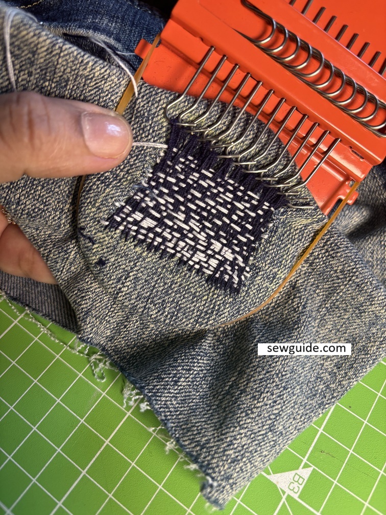 darning over a hole in jeans - visible mending